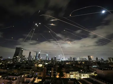 Trajetórias de mísseis e projéteis cortando o céu noturno de Tel Aviv, durante um ataque com sistema de defesa aérea em ação, refletindo a escalada do conflito entre Israel e Irã. A cidade iluminada ao fundo contrasta com os rastros luminosos dos interceptadores, simbolizando tensão geopolítica e crise no Oriente Médio.