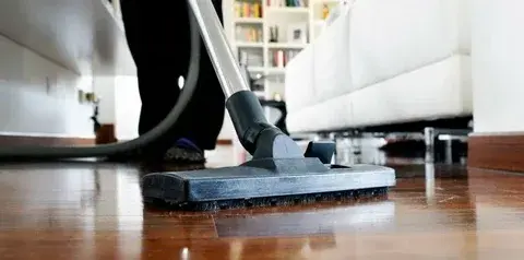 Person vacuuming hardwood floor in a living room