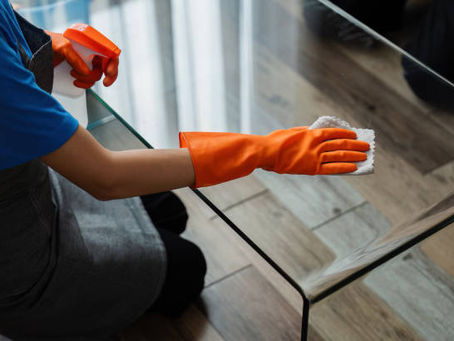 Person wearing orange gloves cleaning a glass table