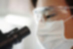 Student in mask and goggles using a microscope