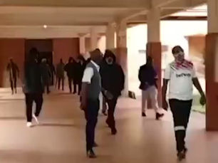 A Hooded Man Walking Through a Building Corridor