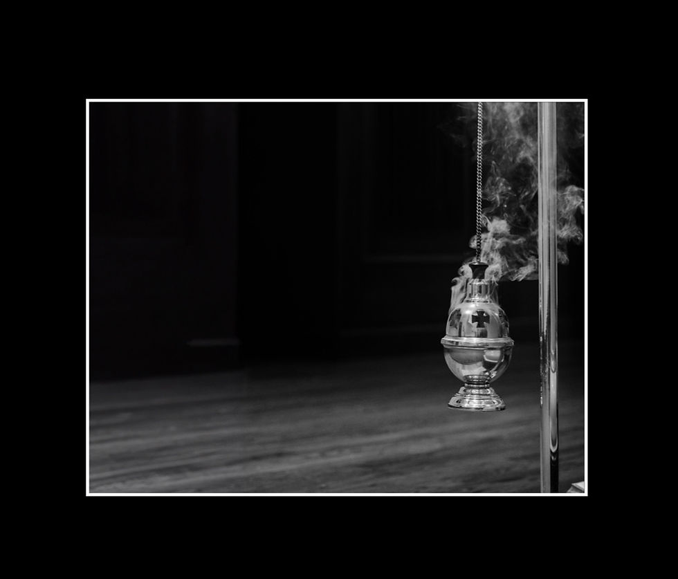 Black and white photo of a thurible emitting smoke with a back border