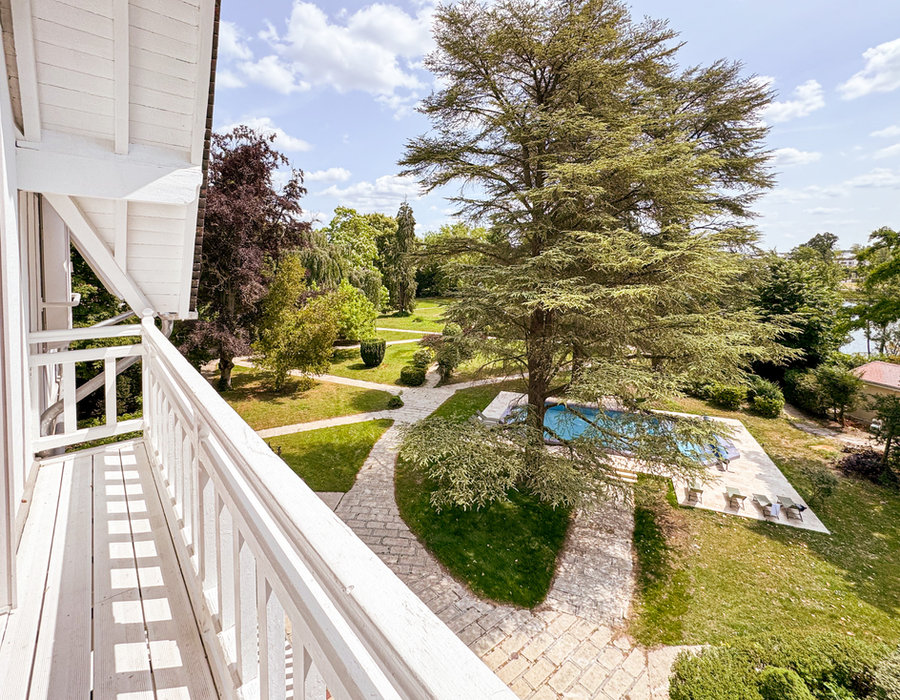 Vue depuis le balcon du Manoir : les cèdres centenaires, la piscine et le parc