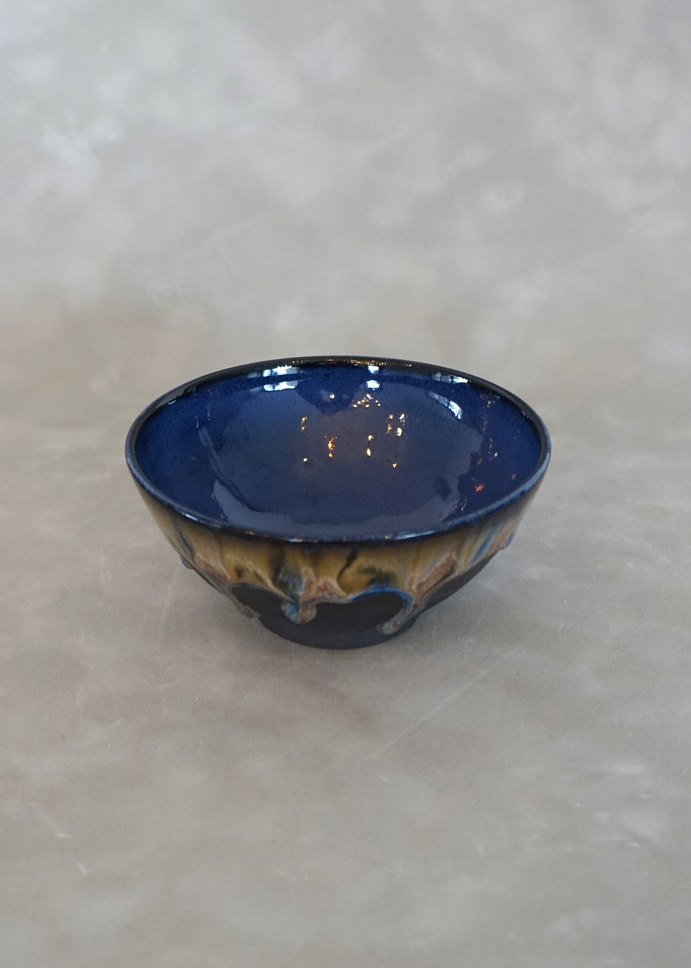 Thumbnail: ceramic bowl with a brown, pink and blue glaze with indigo interior