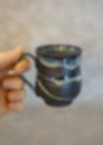 small black and green espresso cup in a hand side view