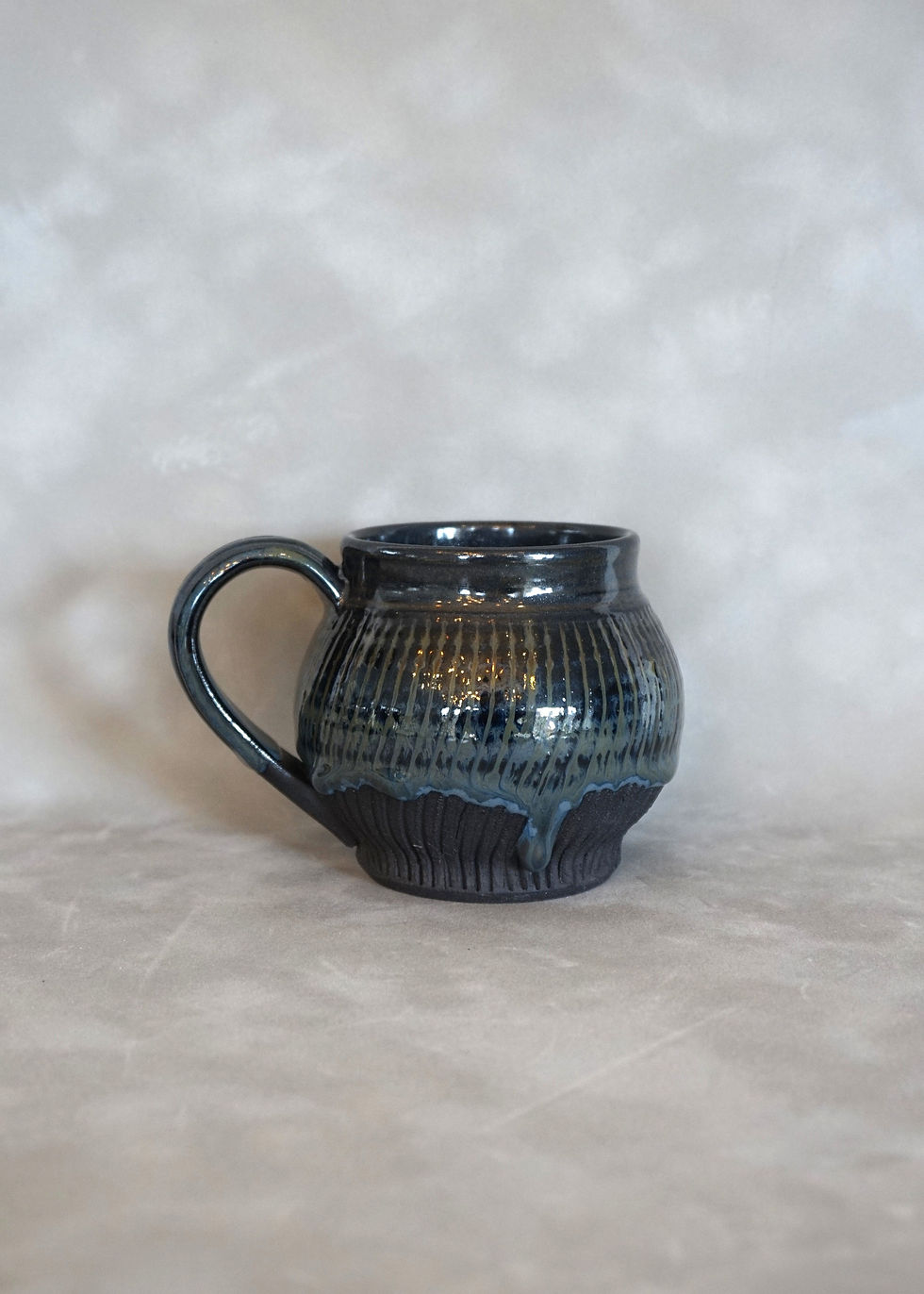 Thumbnail: black clay globe mug with a sparkly black glaze side view