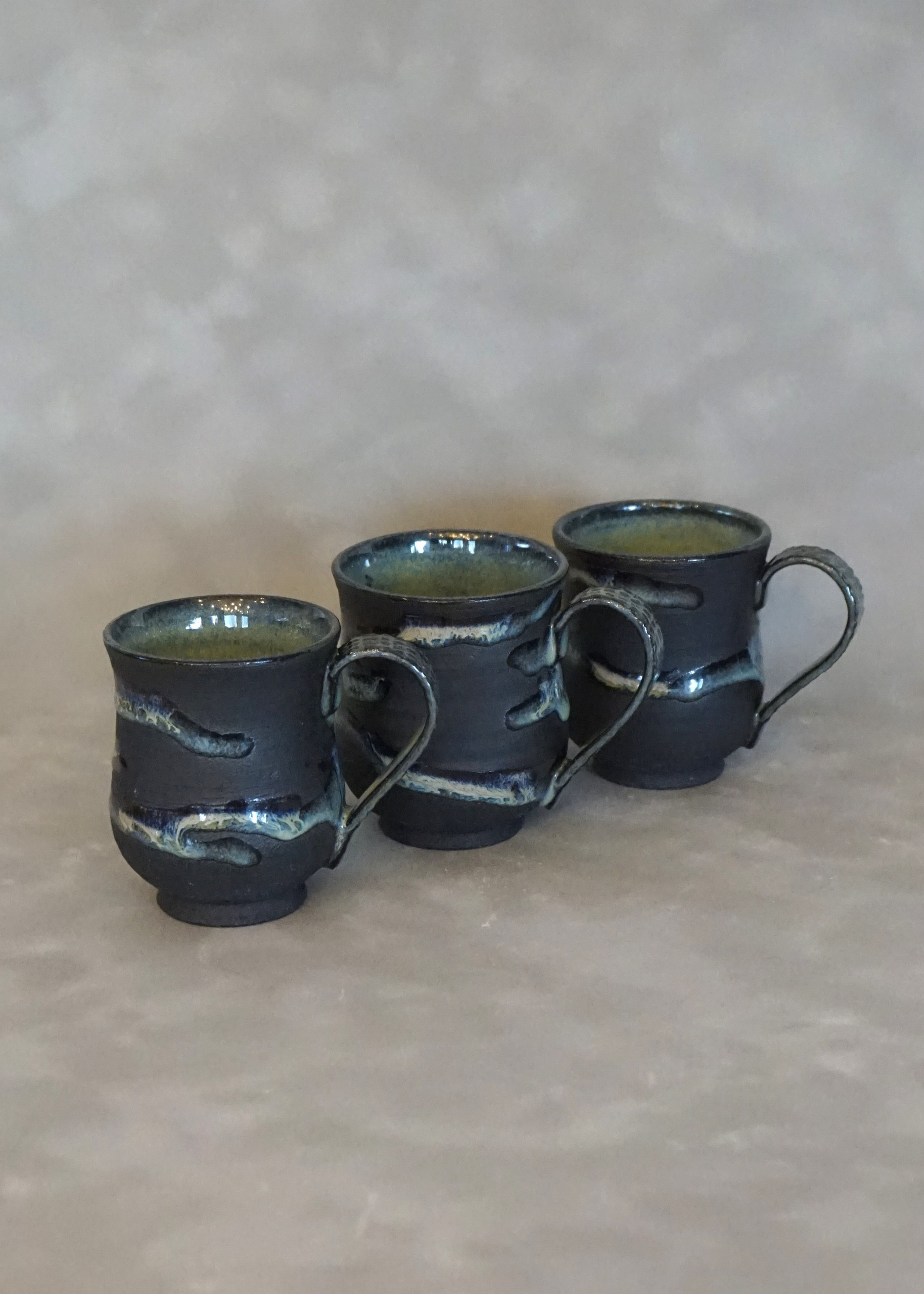 3 small black and green espresso cups side view
