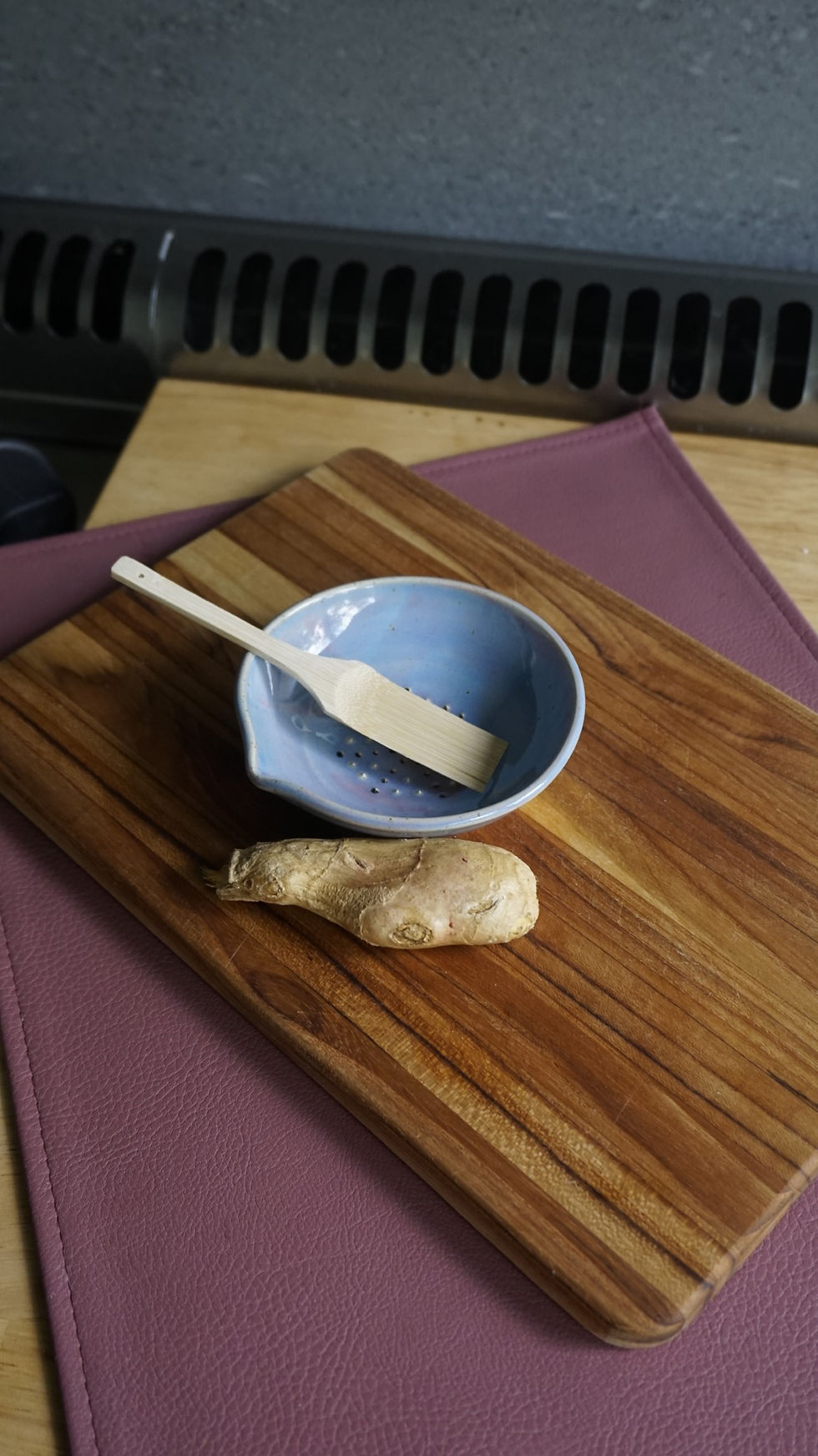 Thumbnail: Blue stoneware garlic grater with a piece of garlic and grater brush
