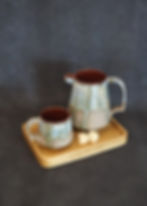 Personal ceramic coffee set with a green, blue and red glaze on a wooden tray with sugar cubes