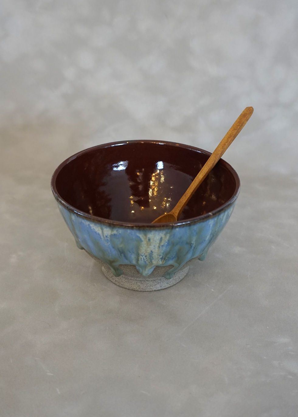 Thumbnail: ceramic cereal bowl with a blue and green glaze and red interior with a wooden spoon