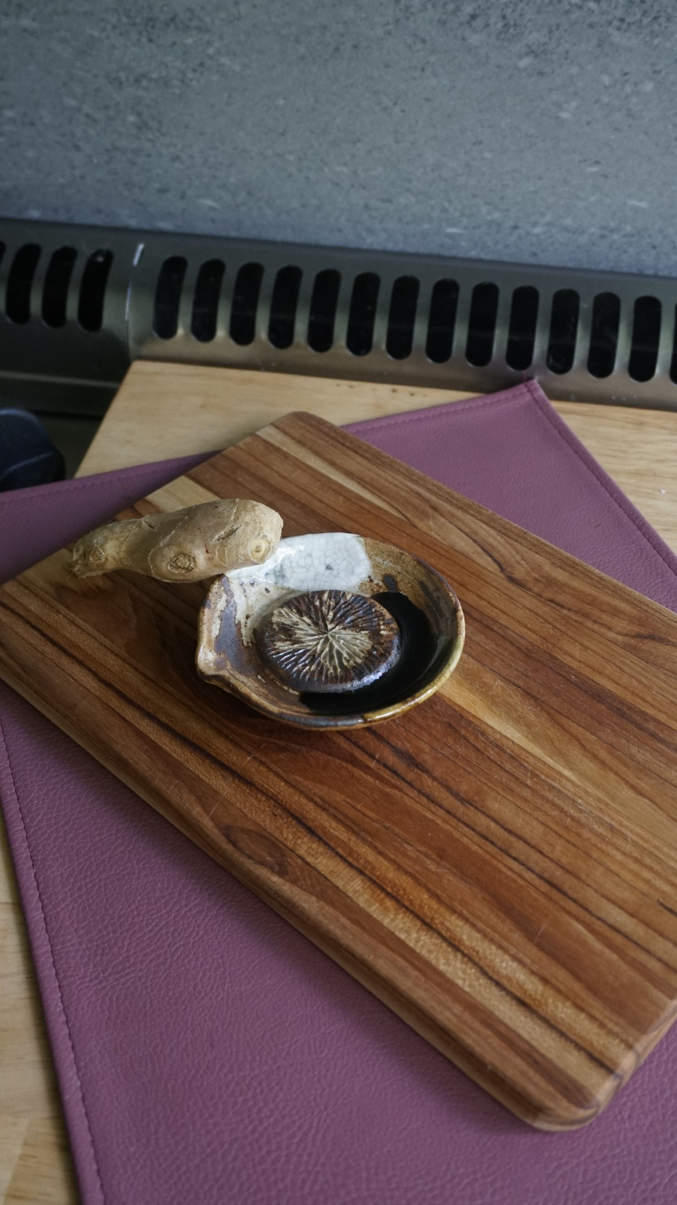 White, green and brown pottery ginger grater with a piece of ginger top view