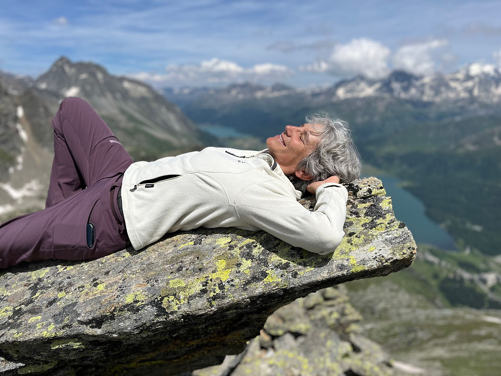 Susanne Hollenstein liegt lächend auf einem Felsen. Im Hintergrun sieht man die Oberengadiner Seen