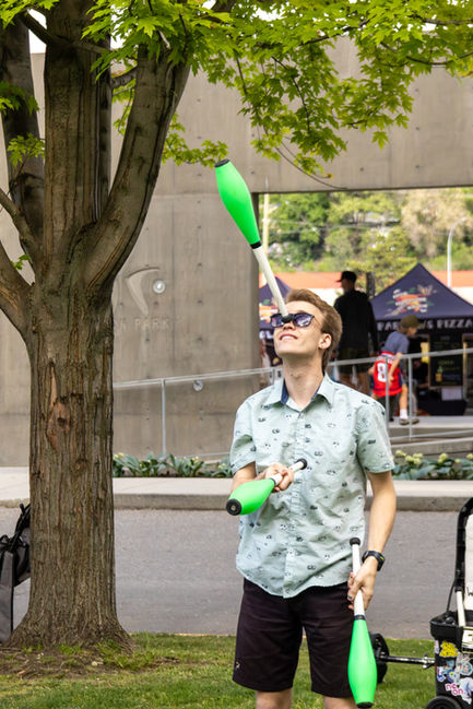 a man juggling a green juggling stick in front of a sign that says park park