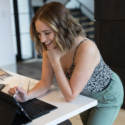 a woman sitting at a desk with a tablet and a pen
