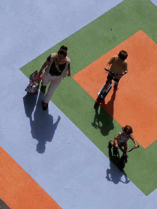 Personas caminando y niños en bicicleta sobre el espacio peatonal intervenido por EZKA en Laudio.