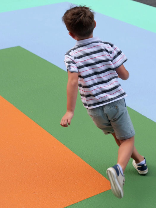 Niño corriendo sobre el pavimento de colores de EZKA en una calle peatonal de Laudio.