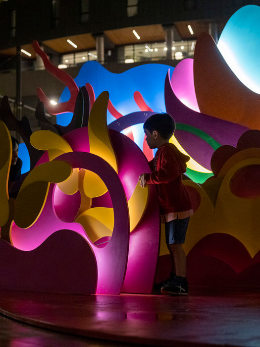 Niño explorando entre las formas iluminadas de la instalación interactiva POP-UP.