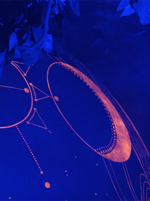 Detalle nocturno de gráfica astronómica iluminada sobre una escultura de la instalación KOSMOS.