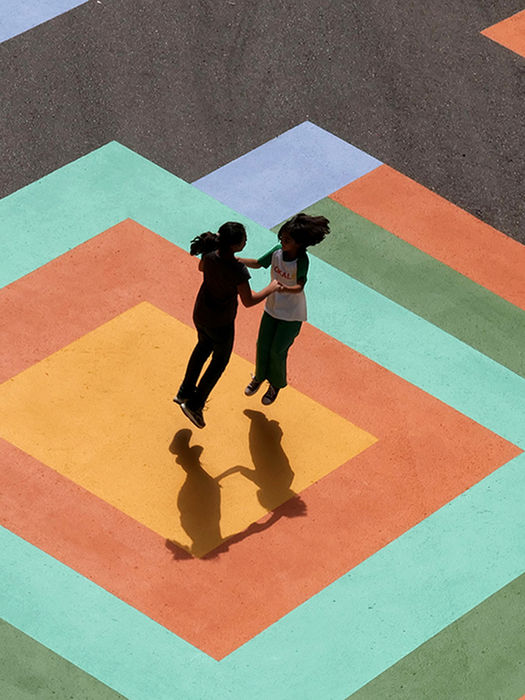 Dos personas bailando sobre el mural de pavimento de EZKA en un espacio público peatonal de Laudio.