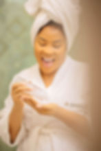 Abiola Ahmed Kass CEO Hush'D Makeover in a bathrobe using Rice Glow Toner and smiling