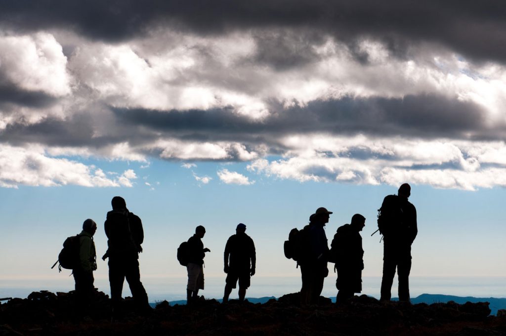 Group of hikers shadowed against blue sky