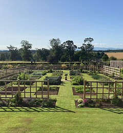 Large formal garden with oak trellis structures and landscaped planting beds.