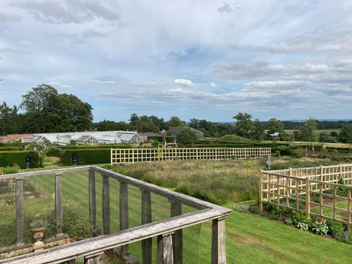 Large garden with greenhouses and oak trellis dividers, surrounded by countryside views