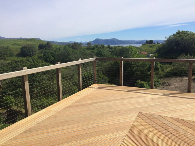 Raised timber deck with wire balustrade overlooking hills and sea views on Skye Scotland