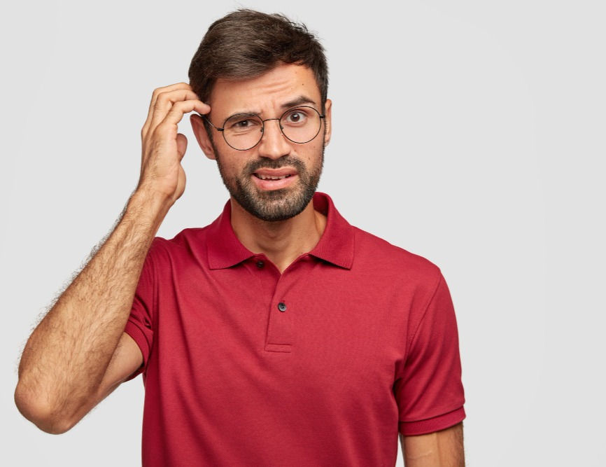 A person scratching their head, pondering where to make an investment.
