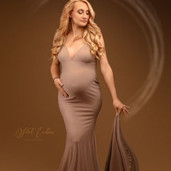 Femme enceinte pose élégamment en robe pour shooting grossesse.