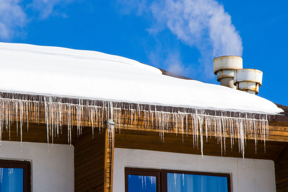 Close-up of ice dam and long icicles hanging from a snow-covered roof on a residential home.