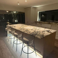 Modern kitchen with a large marble island featuring five bar stools