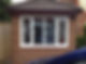 A rectangular bay window with white frames set in a red brick wall reflects a parked vehicle