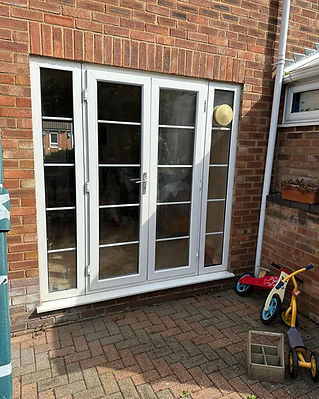 White French doors on a red brick wall open to a patio