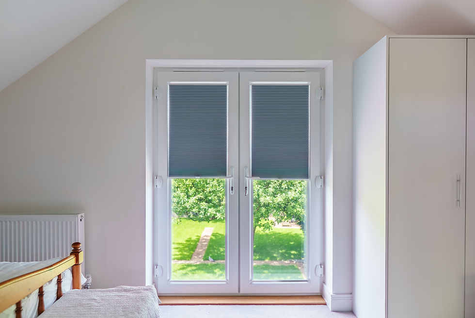 White patio doors with integrated grey blinds opening onto a green garden view