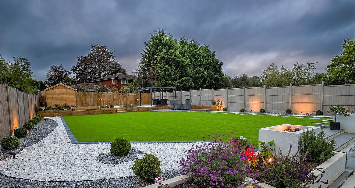 A wide shot of a large, professionally landscaped back garden showcasing an expansive artificial lawn