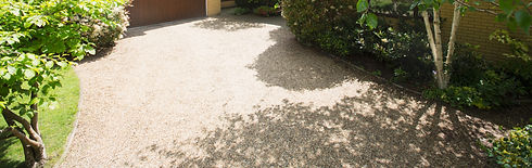Smooth beige resin bound aggregate driveway laid outside a house garage