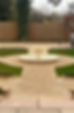 A circular fountain at the center of a well-manicured gravel garden