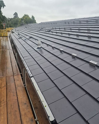 Rows of clean dark grey roof tiles freshly installed on a residential building