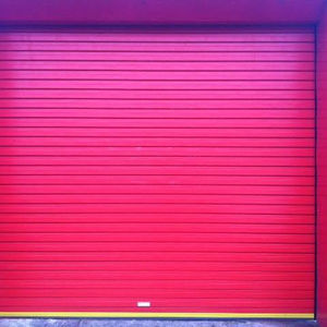 Red roller shutter door fitted on a vibrant commercial storefront