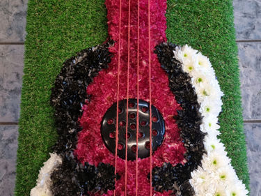 Floral arrangement shaped like a guitar on green grass