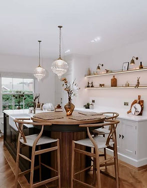 Modern kitchen with a wooden island, round seating, and elegant pendant lights