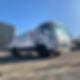 Large white commercial tanker truck parked on a gravel site under a clear blue sky