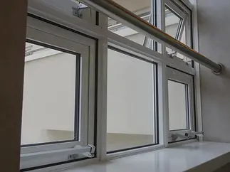 Rows of rectangular windows with white frames, slightly open, reveal a pale exterior wall