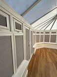uPVC conservatory fitted with grey pleated blinds and wooden floor