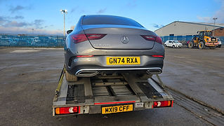 A car is being carefully loaded onto a flatbed truck for transport