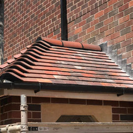 Brick wall with a small roof featuring red and black tiles