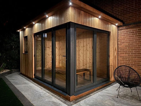 Modern wooden shed with a slanted roof and glass doors, softly lit by outdoor lights
