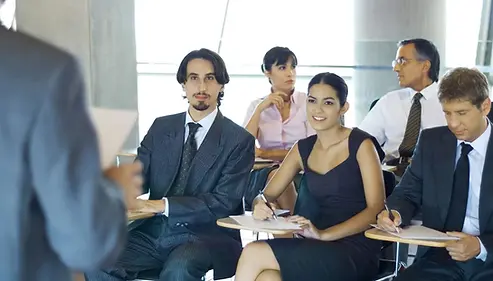 Male and female professionals seated in a classroom