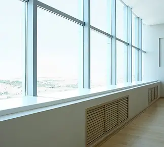 Large floor-to-ceiling windows with a clear, sunny view, white walls, and light wood flooring